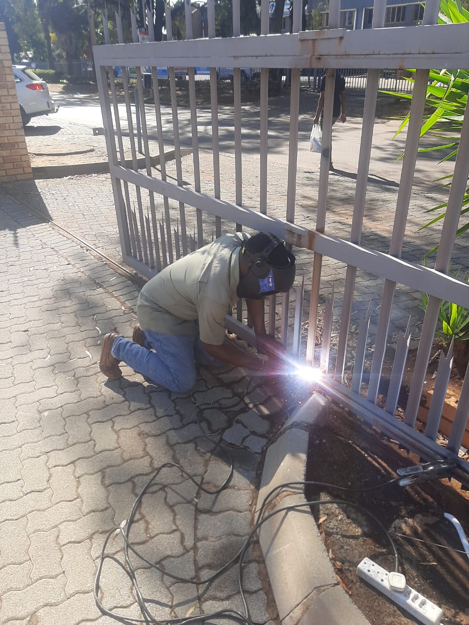 LK Ndebele Security Systems technician welding a steel palisade gate on site